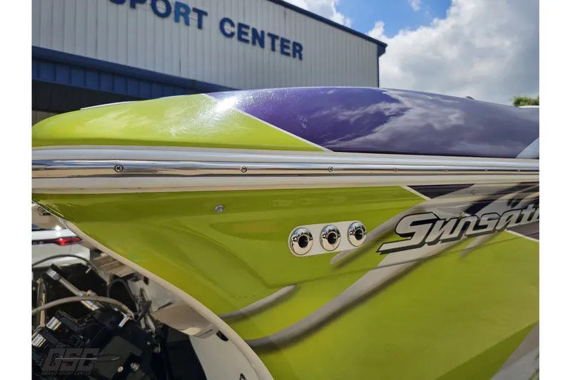 Slide: The Image of 2007 Sunsation 32 Dominator boat with vibrant green and purple design at a sport center. - 107