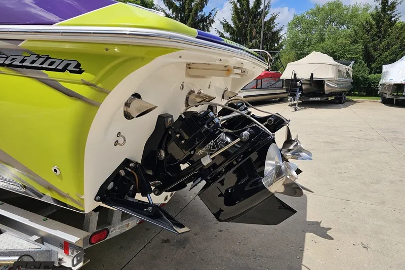 Slide: The Image of 2007 Sunsation 32 Dominator boat with vibrant green and purple exterior, parked on a trailer. - 28