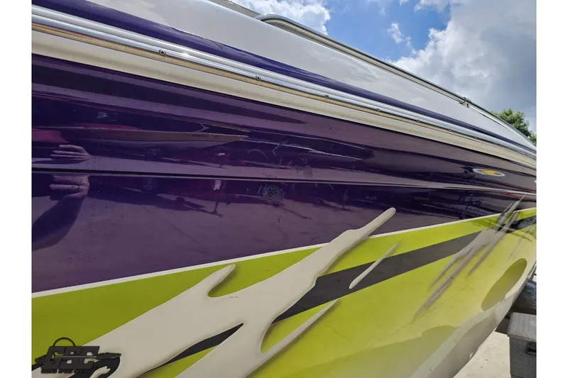 Slide: The Image of 2007 Sunsation 32 Dominator boat with vibrant purple and yellow graphics under a blue sky. - 108