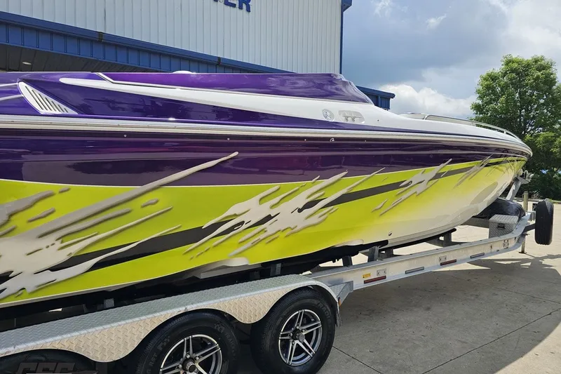 Slide: The Image of 2007 Sunsation 32 Dominator boat with vibrant purple and yellow design on trailer. - 10