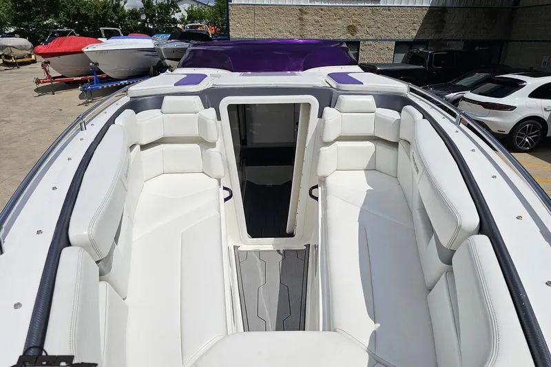 Slide: The Image of 2007 Sunsation 32 Dominator boat with white seating and purple accents, docked outdoors. - 16