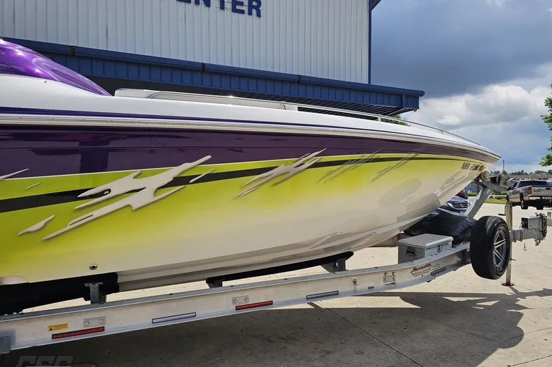 Slide: The Image of 2007 Sunsation 32 Dominator boat with vibrant purple and yellow design on trailer. - 6