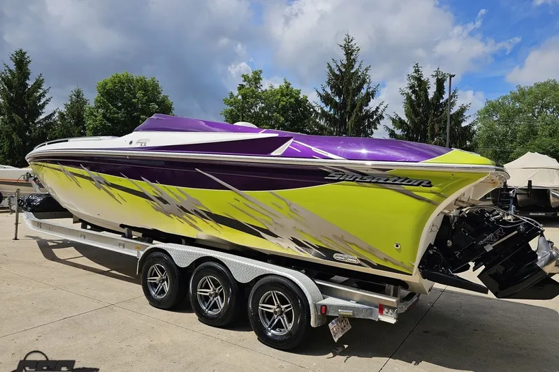 Slide: The Image of 2007 Sunsation 32 Dominator boat with vibrant purple and yellow design on a trailer. - 27