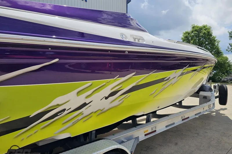 Slide: The Image of 2007 Sunsation 32 Dominator boat with vibrant purple and yellow design on trailer. - 9