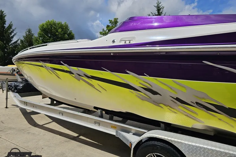 Slide: The Image of 2007 Sunsation 32 Dominator boat with vibrant purple and yellow design on a trailer. - 25