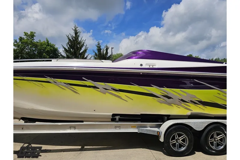 Slide: The Image of 2007 Sunsation 32 Dominator boat with vibrant purple and yellow graphics on a trailer. - 21