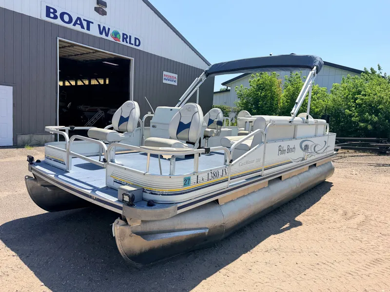Slide: The Image of A 2004 Palm Beach CastMaster pontoon boat with a 50HP Mercury 4Stroke engine, parked outside a building. - 47