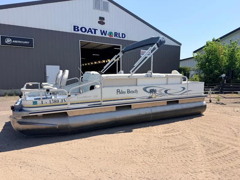 Slide: The Image of A 2004 Palm Beach CastMaster pontoon boat with a 50HP Mercury 4Stroke engine, parked outside a building. - 49
