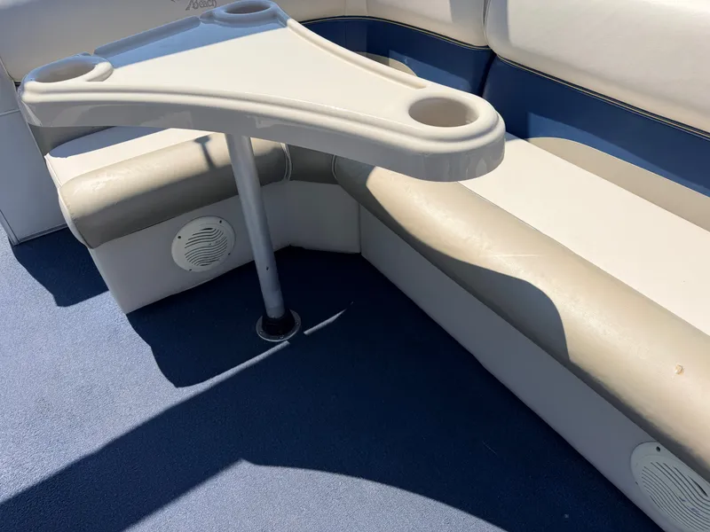 Slide: The Image of A boat with blue and white seating and a small table with cup holders. - 33