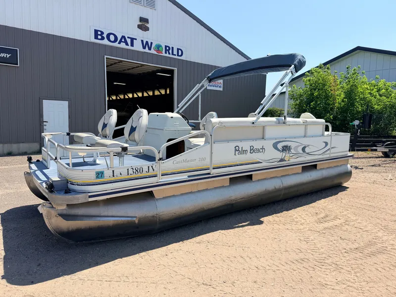 Slide: The Image of 2004 Palm Beach 200 CastMaster with 50HP Mercury 4Stroke, pontoon boat on sand in front of a building. - 48