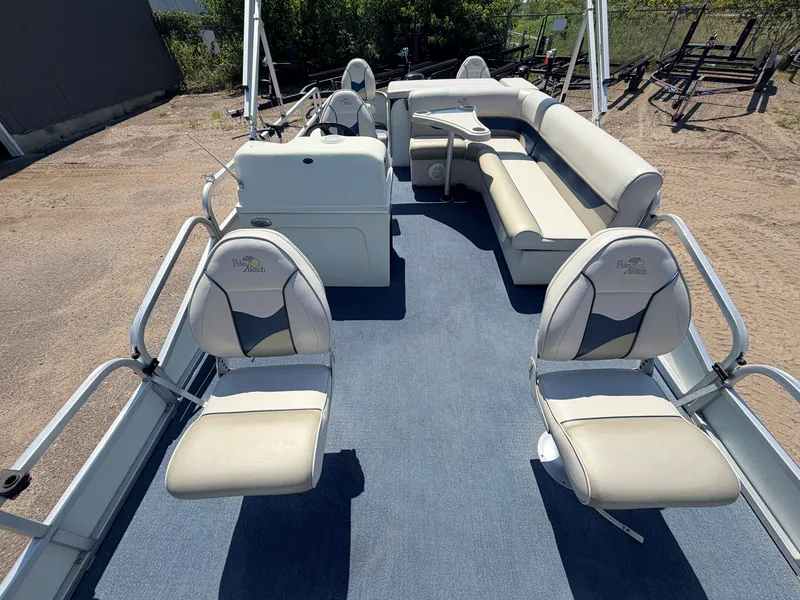 Slide: The Image of The image shows the deck of a 2004 Palm Beach 200 CastMaster boat with beige seats and blue carpeting. - 2
