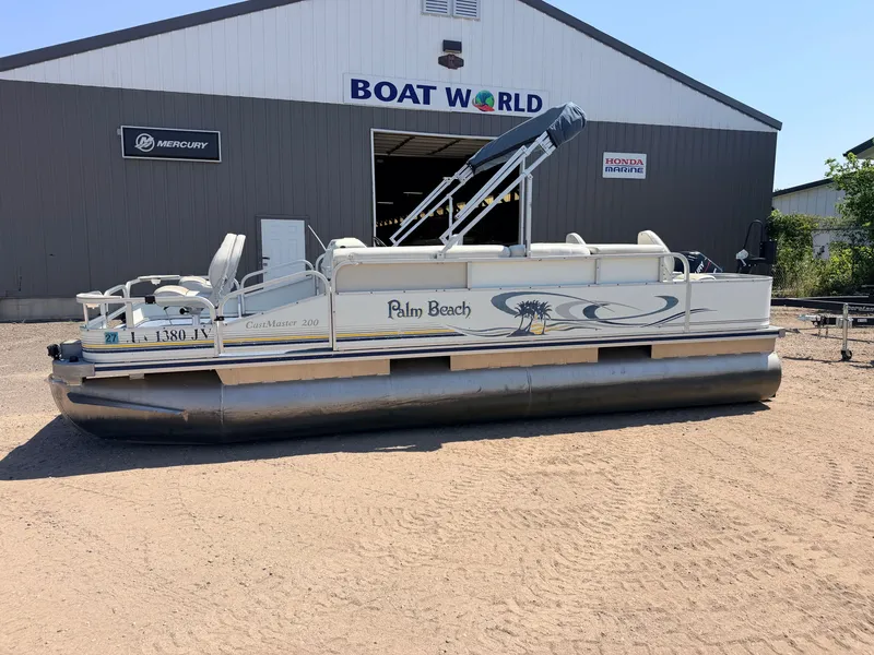 Slide: The Image of Palm Beach CastMaster 200 pontoon boat with 50HP Mercury 4-stroke engine, 2004 model, in front of a boat shop. - 50