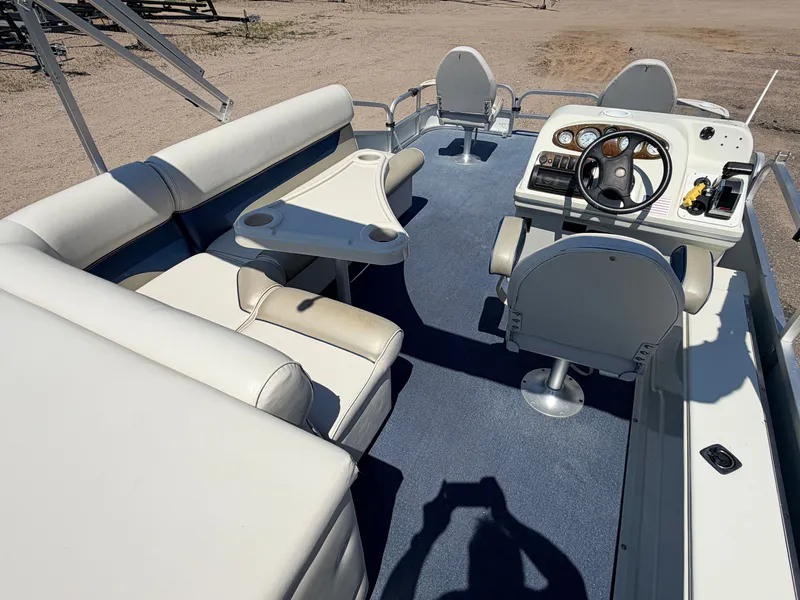 Slide: The Image of The image shows the cockpit of a 2004 Palm Beach 200 CastMaster boat with a 50HP Mercury 4Stroke engine. It features white upholstery, a helm, and a table. - 6