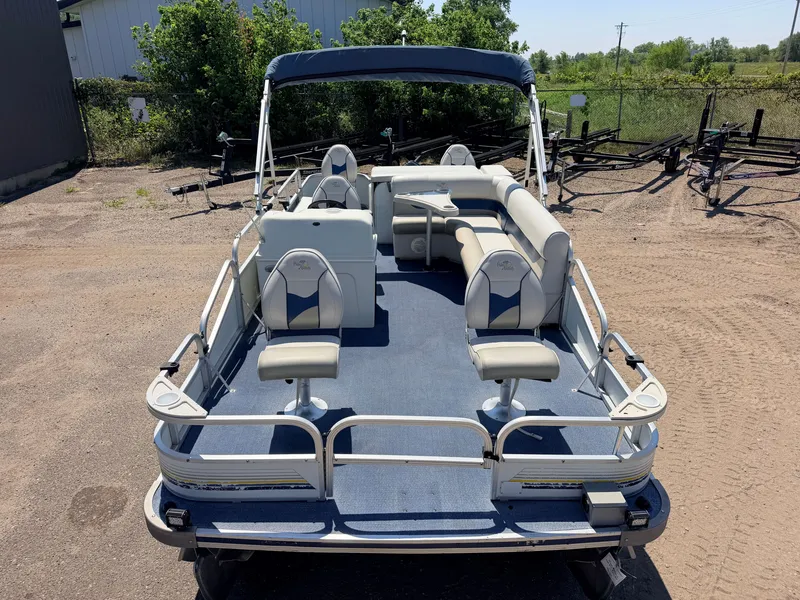 Slide: The Image of A 2004 Palm Beach pontoon boat with blue upholstery and a sunshade, parked on sandy ground. - 10