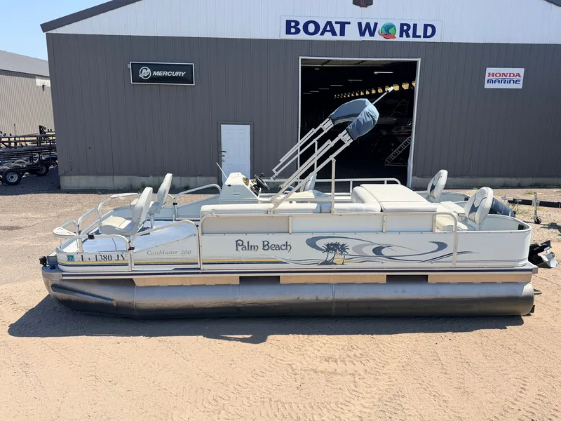 Slide: The Image of A 2004 Palm Beach CastMaster pontoon boat with a 50HP Mercury 4Stroke engine, parked outside a building. - 4