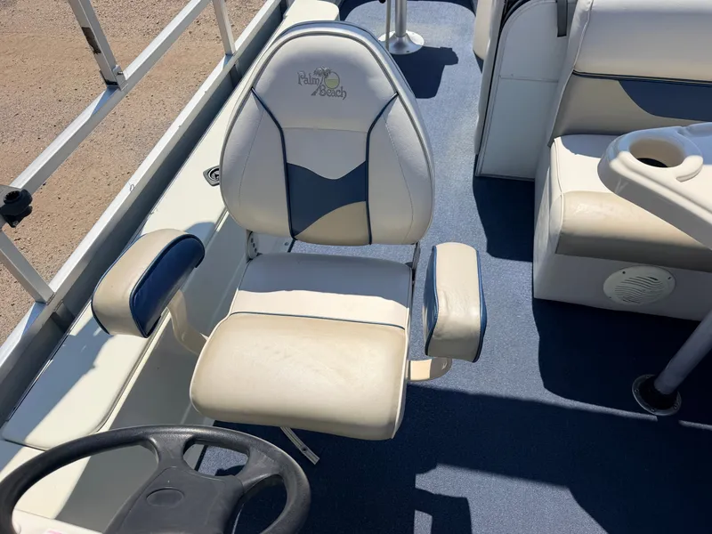 Slide: The Image of A 2004 Palm Beach boat featuring a comfortable seat and steering wheel on blue flooring. - 22