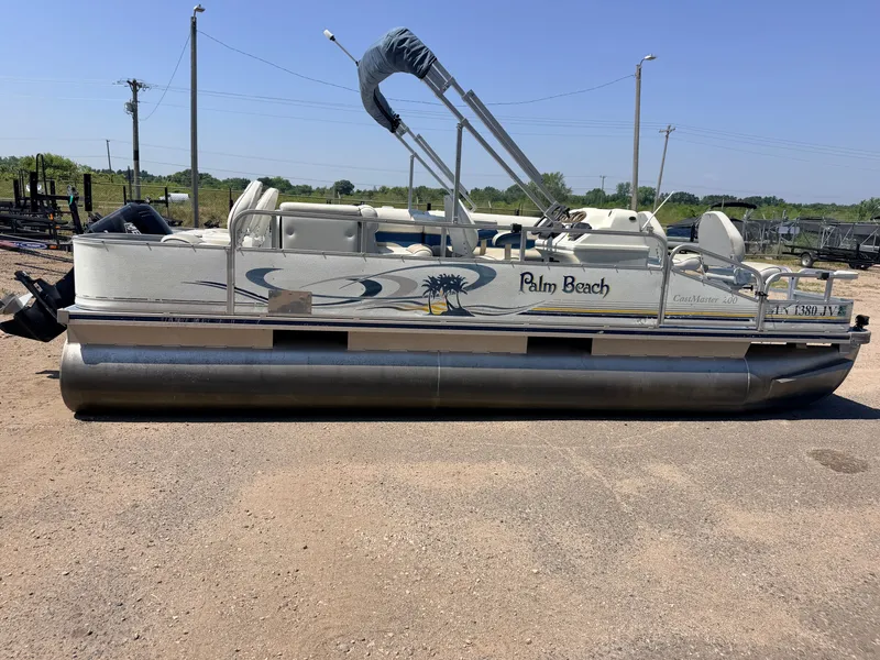 Slide: The Image of A silver Palm Beach pontoon boat, 2004 model, is parked on dry ground. - 19