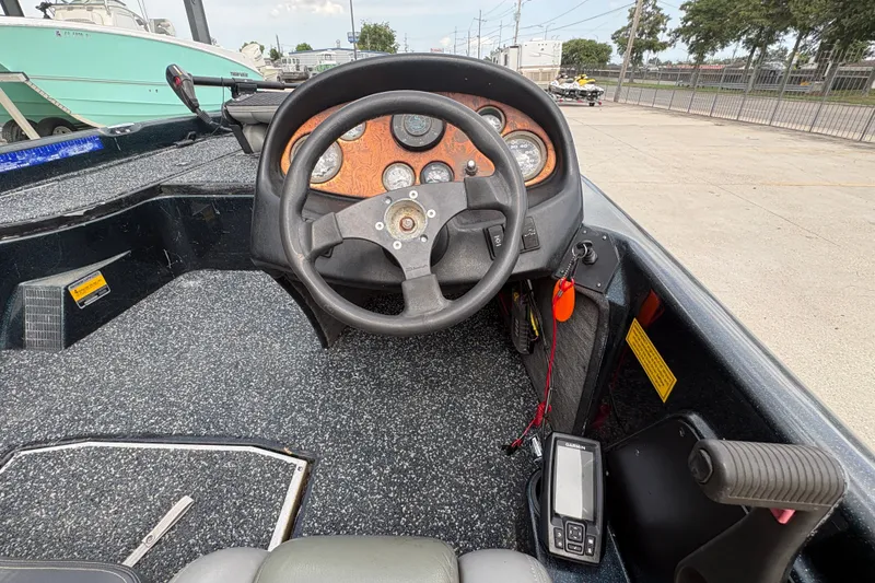 Slide: The Image of 1998 Triton Tr-17 boat dashboard with steering wheel and gauges in a marina setting. - 13