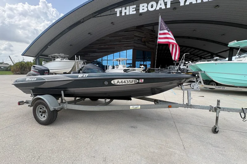 Slide: The Image of 1998 Triton Tr-17 boat on trailer at a boat yard with American flag. - 1