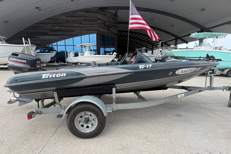 Slide: The Image of 1998 Triton Tr-17 boat on trailer with Johnson V4 engine, American flag in background. - 2
