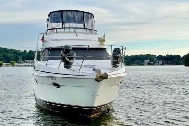 Slide: The Image of 2004 Carver 420 Mariner yacht on a serene lake with lush green shoreline. - 3