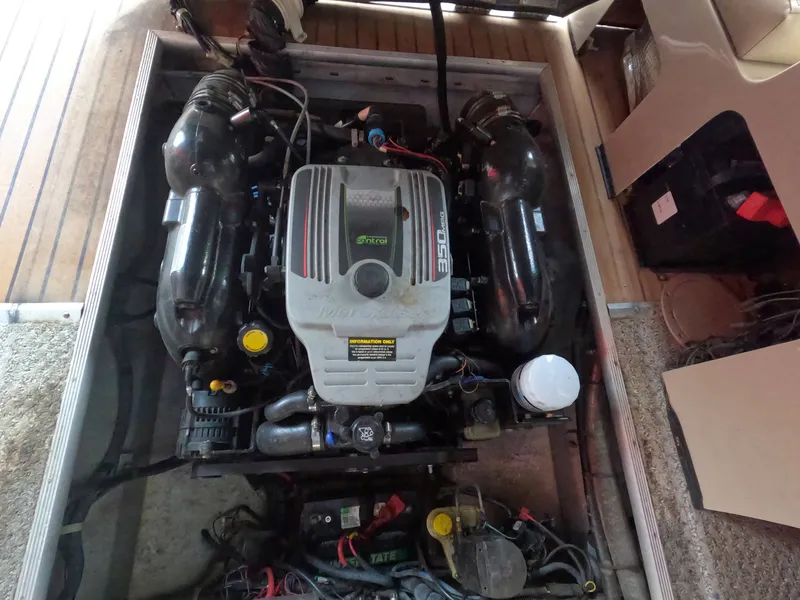 Slide: The Image of An engine compartment with a large engine, surrounded by cables and hoses, inside a boat. - 8