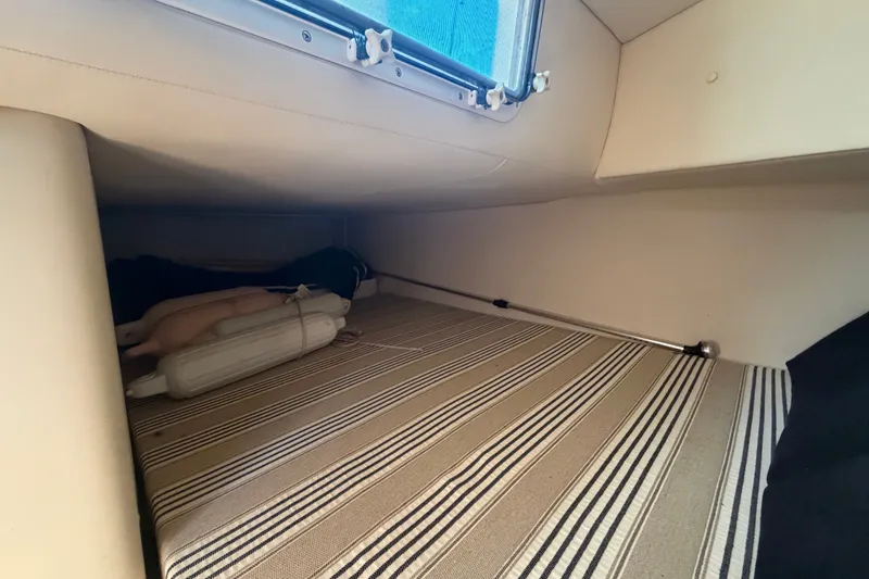 Slide: The Image of 2016 Glastron GS 259 cabin interior with striped upholstery and window view. - 48