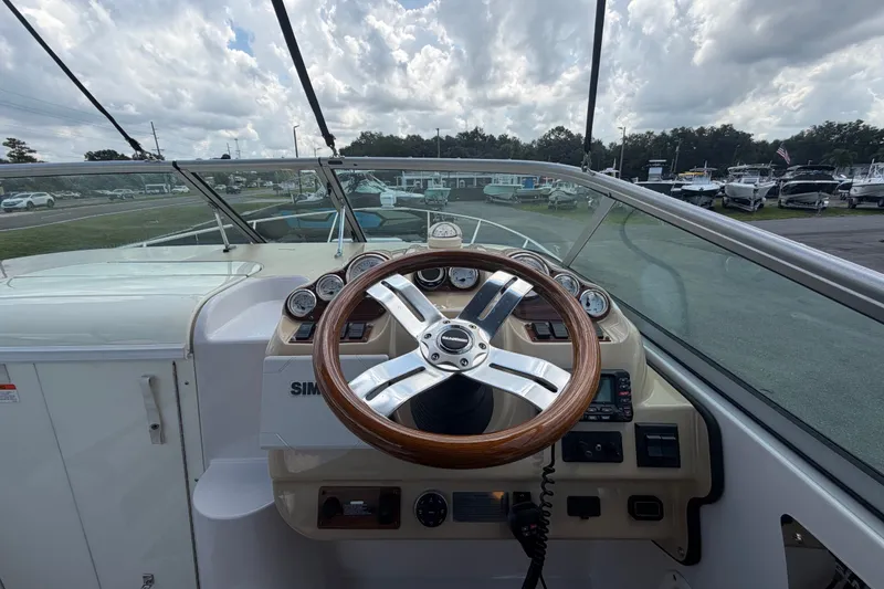Slide: The Image of 2016 Glastron GS 259 boat helm with wooden steering wheel and dashboard controls. - 29