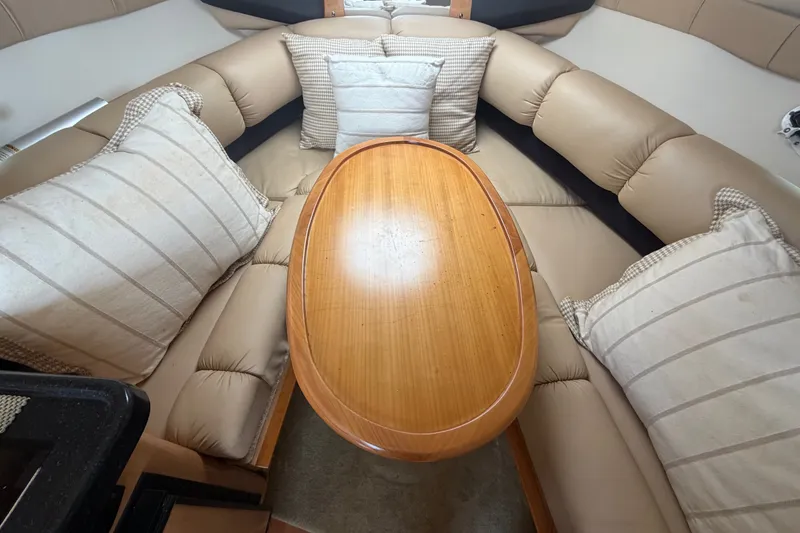 Slide: The Image of Interior of 2016 Glastron GS 259 boat with cushioned seating and wooden table. - 62