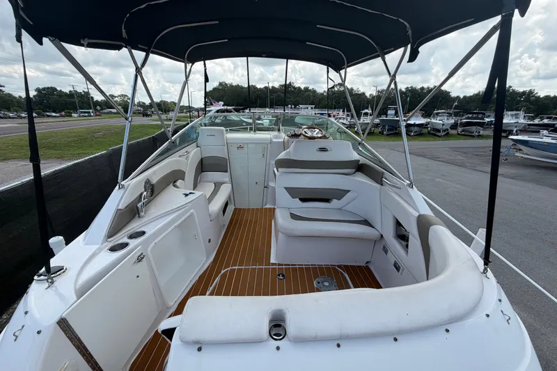 Slide: The Image of 2016 Glastron GS 259 boat interior with seating, canopy, and wood-style flooring. - 13