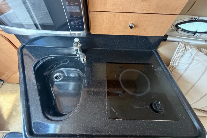 Slide: The Image of Compact kitchen area in a 2016 Glastron GS 259 boat with sink and stove. - 56