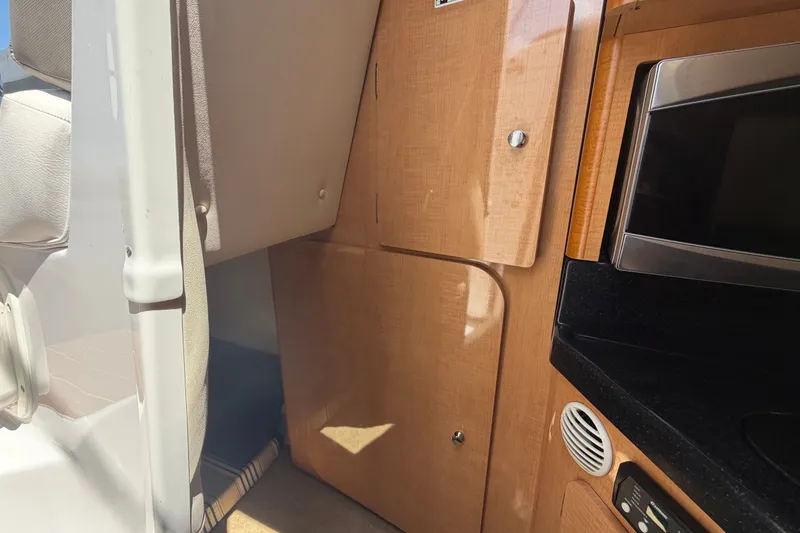 Slide: The Image of Interior of a 2016 Glastron GS 259 boat, featuring wood cabinetry and a microwave. - 44