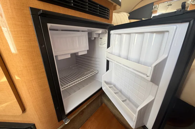Slide: The Image of Open refrigerator inside 2016 Glastron GS 259 boat, showcasing interior shelves and storage. - 58
