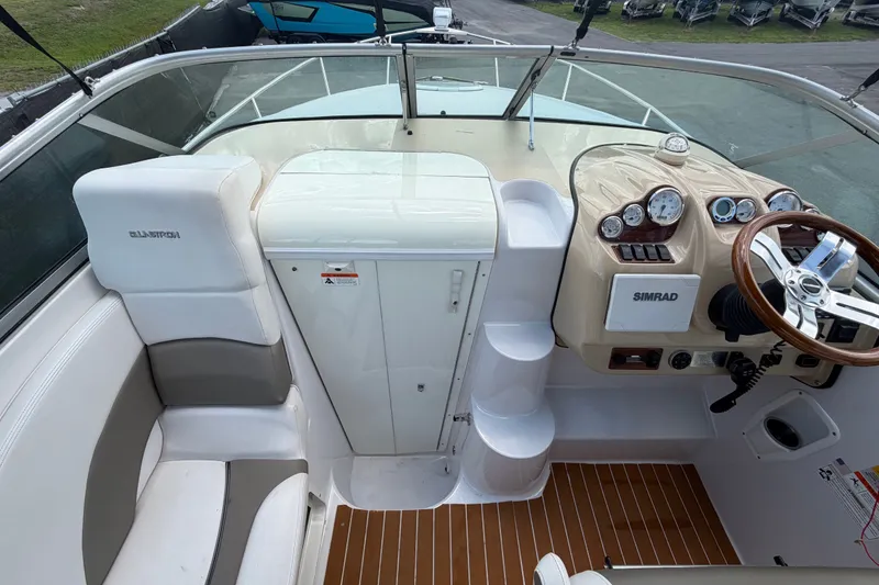 Slide: The Image of 2016 Glastron GS 259 boat cockpit with steering wheel, gauges, and seating area. - 26