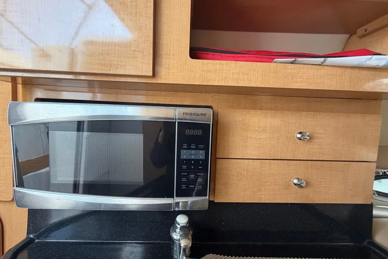 Slide: The Image of Microwave in 2016 Glastron GS 259 boat kitchen with wooden cabinets and black countertop. - 54