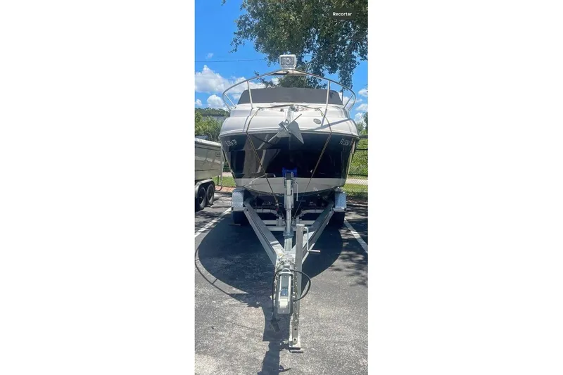 Slide: The Image of 2016 Glastron GS 259 boat on trailer, parked outdoors under a clear blue sky. - 10