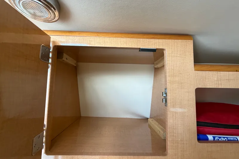 Slide: The Image of Open wooden cabinet inside 2016 Glastron GS 259 boat, showcasing storage space. - 53