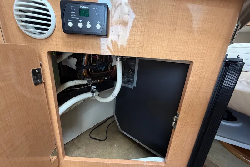Slide: The Image of 2016 Glastron GS 259 boat interior showing control panel and open cabinet with wiring. - 50