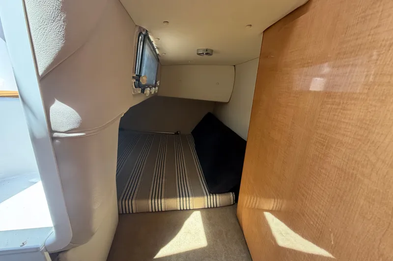 Slide: The Image of 2016 Glastron GS 259 cabin interior with striped bedding and wooden paneling. - 47