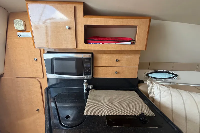 Slide: The Image of 2016 Glastron GS 259 boat interior kitchen with microwave, sink, and storage cabinets. - 51