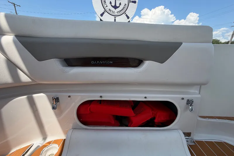 Slide: The Image of 2016 Glastron GS 259 boat storage compartment with red life jackets inside. - 86