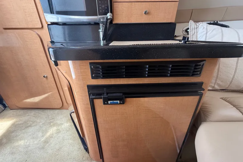 Slide: The Image of 2016 Glastron GS 259 interior kitchen with microwave, sink, and compact refrigerator. - 57