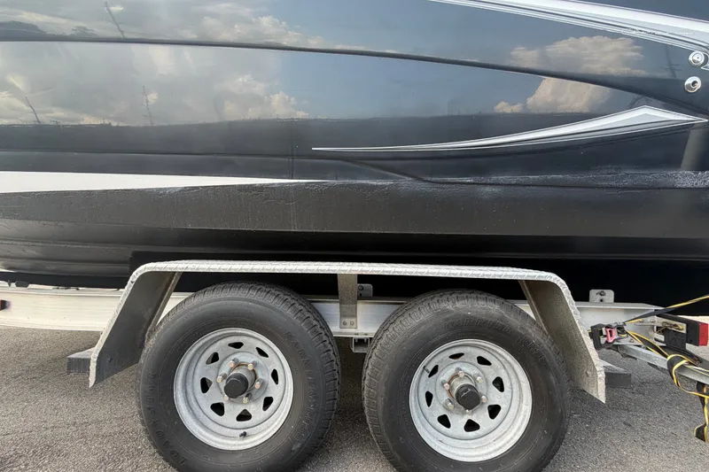 Slide: The Image of Trailer with 2016 Glastron GS 259 boat, black hull, parked on pavement. - 96