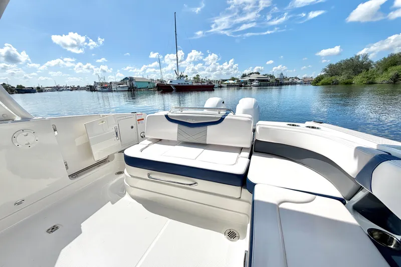 Slide: The Image of 2021 Chaparral 280 OSX boat interior with white seating, docked by a scenic waterfront. - 13