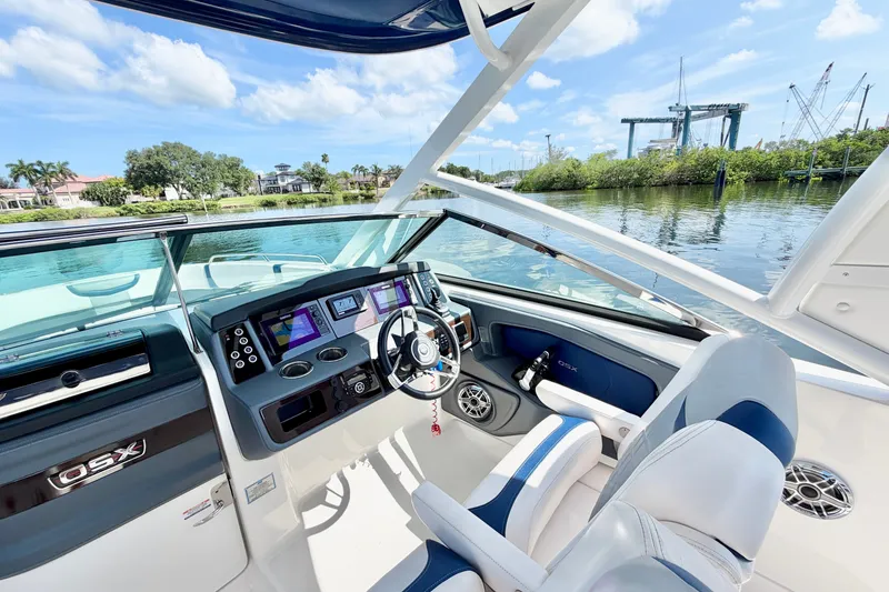 Slide: The Image of 2021 Chaparral 280 OSX boat cockpit with modern controls, steering wheel, and waterfront view. - 18