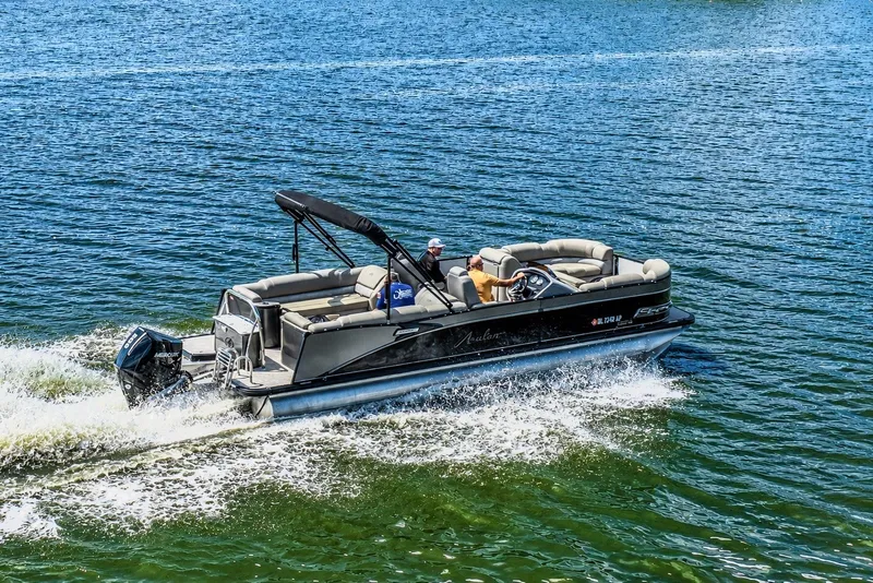 Slide: The Image of 2022 Avalon Catalina Platinum Quad Lounge 25' pontoon boat cruising on a sunny lake. - 2
