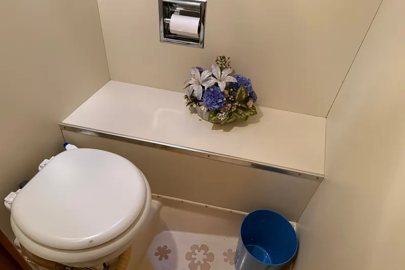 Slide: The Image of 1987 Chris-Craft 362 Catalina bathroom with toilet, floral arrangement, and blue waste bin. - 20