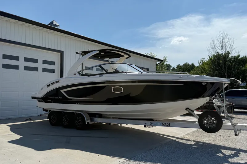 Slide: The Image of 2014 Chaparral 307 SSX boat on trailer, parked outside a garage. - 2
