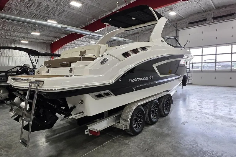 Slide: The Image of 2014 Chaparral 307 SSX boat in a showroom, featuring sleek design and triple-axle trailer. - 3