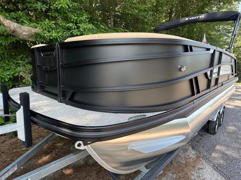 Slide: The Image of A 2027 Evotti 521QL pontoon boat on a trailer, surrounded by trees. - 8